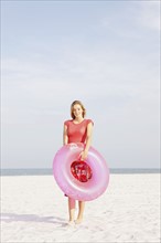 Teenage girl holding inflatable ring on beach. Date : 2008