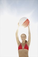 Young woman holding beach ball above head. Date : 2008