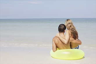 Couple sitting in inflatable ring in shallow ocean. Date : 2008
