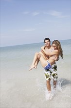 Teenage boy carrying girlfriend in ocean. Date : 2008