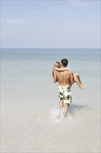 Teenage boy carrying girlfriend in ocean. Date : 2008