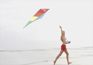 Young woman flying kite on beach. Date : 2008