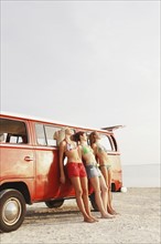 Young women leaning against van on beach. Date : 2008