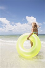 Girl carrying inflatable ring into ocean. Date : 2008