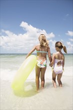 Girls carrying inflatable ring into ocean. Date : 2008