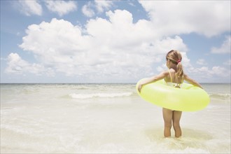 Girl carrying inflatable ring into ocean. Date : 2008
