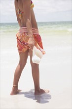Girl standing in ocean holding shell. Date : 2008