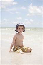 Boy sitting in shallow ocean. Date : 2008