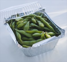 Close up of edamame in takeout container.