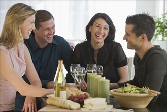 Couples sitting around wine, bread, cheese, and salad.