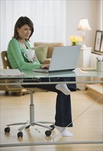 Woman working on laptop in home office.