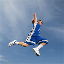 Teenage basketball player in mid-air throwing basketball. Date: 2008