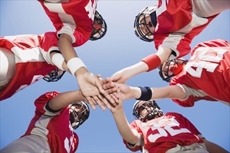 Football players joining hands in huddle. Date: 2008