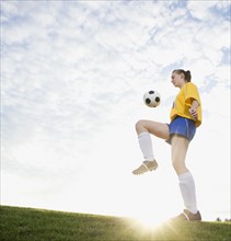 Teenage girl bouncing soccer ball on knee. Date: 2008