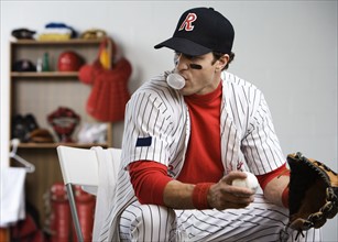 Baseball player blowing bubble with gum in locker room. Date : 2008