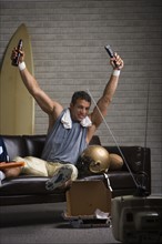Football player watching football and cheering on sofa. Date: 2008