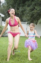 Mother and daughter running through sprinkler. Date: 2008