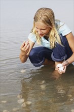Girl finding seashells in ocean. Date: 2008