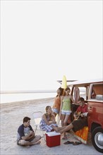 Friends lounging around van on beach. Date : 2008