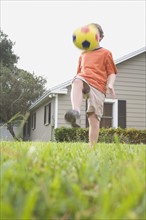 Boy in backyard kicking soccer ball. Date : 2008