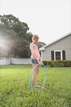 Girl standing in backyard with hula hoop. Date: 2008