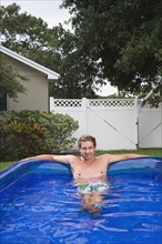 Portrait of man soaking in inflatable swimming pool. Date: 2008