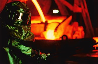Worker in asbestos suit working in steel foundry. Date: 2008