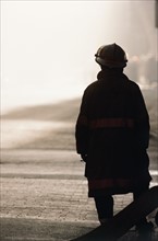 Silhouette of fireman looking at smoke in distance. Date: 2008