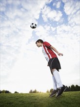 Boy in uniform bouncing soccer ball off head. Date: 2008
