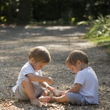 Toddler boys playing with pebbles. Date: 2008