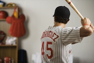 Baseball player practicing swing in locker room. Date: 2008