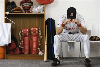 Baseball player sitting with head down in locker room. Date : 2008