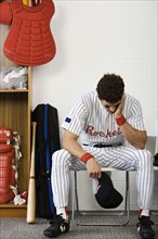 Baseball player sitting with head in hands in locker room. Date : 2008