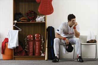 Baseball player sitting in locker room looking pensive. Date : 2008