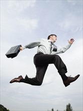 Businessman with briefcase jumping in mid-air. Date : 2008