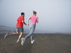 Couple jogging on foggy beach. Date : 2008