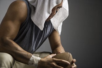 Football player with towel on head holding football. Date : 2008