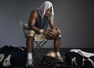 Football player with towel on head in locker room. Date : 2008