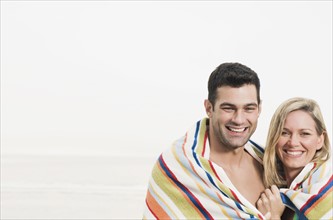 Portrait of couple wrapped in towel at beach. Date: 2008