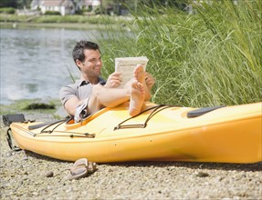 Man reading newspaper in kayak. Date : 2008
