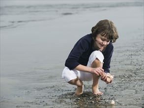Girl finding seashells on beach. Date: 2008