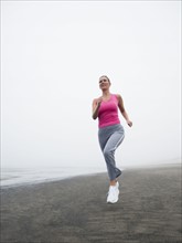 Woman jogging on foggy beach. Date : 2008