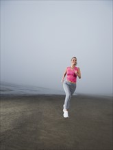 Woman jogging on foggy beach. Date : 2008