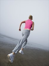 Woman jogging on foggy beach. Date: 2008