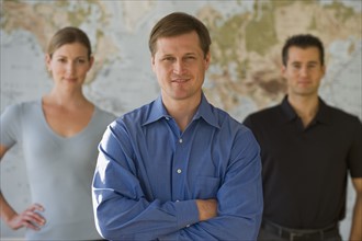 Portrait of business people standing in front of map.