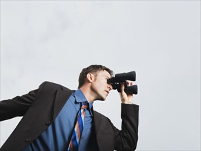 Businessman looking through binoculars. Date: 2008