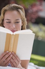 Woman reading book outdoors.