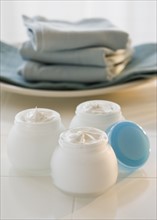 Jars of moisturizing creams and stack of towels.