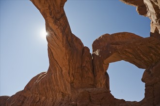 Sun shining behind Double Arch of Arches National Park, Utah.