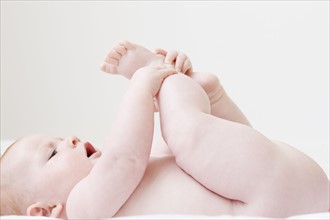 Naked baby laying on back and grabbing feet. Date : 2008